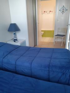 sypialnia z niebieskim łóżkiem i stołem z lampką w obiekcie Royan accès direct à la plage w mieście Royan