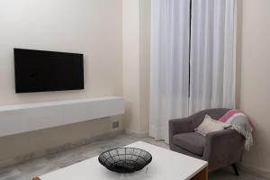 - un salon avec une télévision, une chaise et une table dans l'établissement El Arenal apartment, à Séville