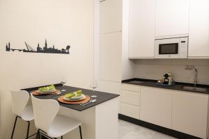 une cuisine avec des placards blancs et une table avec des assiettes de nourriture dans l'établissement El Arenal apartment, à Séville