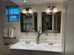 a bathroom with two sinks and two mirrors at Carbone's Beachside Guest Rooms in Sylvan Beach