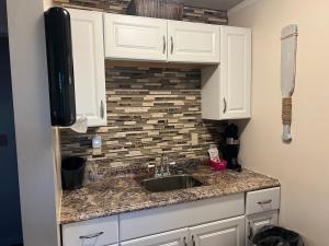a kitchen with a sink and a tile wall at Carbone's Beachside Guest Rooms in Sylvan Beach