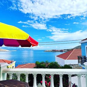 a view of the ocean from a balcony with an umbrella at Roulas Apartments in Halki
