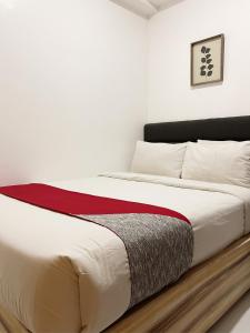 Airo Suites Makati في مانيلا: سرير ابيض وعليه بطانيه حمراء وبيضاء