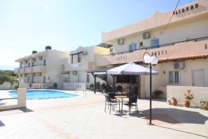 a hotel with a pool and a table with chairs and an umbrella at ilissos Apartments in Stalida