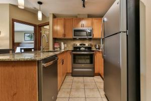 una cocina con electrodomésticos de acero inoxidable y armarios de madera en B&B Falcon Crest Lodge 1BR 1Pullout en Canmore