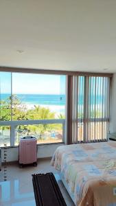 a bedroom with a bed and a view of the ocean at Felicidade in front sea in Saquarema