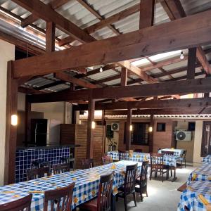 a dining room with tables and chairs and wooden ceilings at Suítes Itaigara a 80 metros da praia do Mariscal in Bombinhas