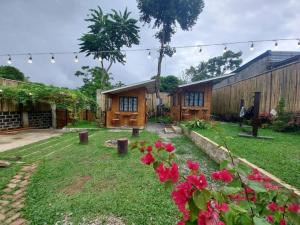 un patio con flores rojas y una casa en Glamping Site walking distance to Majayjay Falls, en Amonoy