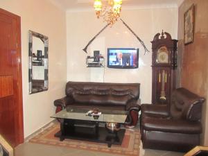 a living room with a leather couch and a clock at Salam Appartement Agadir in Agadir