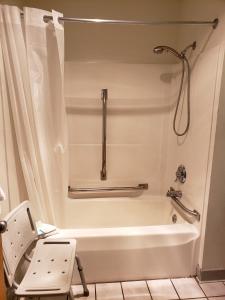 a bathroom with a bath tub and a chair at Fields Park Motel in Wisconsin Dells