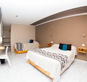 エル・カラファテにあるAmigo del Mundo Hostería y Apart Hotelのベッド2台とテーブルが備わるホテルルームです。