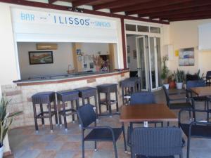 a restaurant with a bar with chairs and tables at ilissos Apartments in Stalida