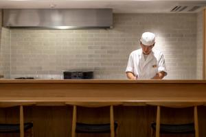 uno chef in piedi dietro un bancone in cucina di Sensui a Toyooka