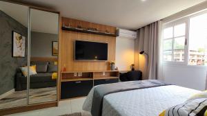 a bedroom with a bed and a flat screen tv at Flat Sunshine - Granja Brasil Resort - Itaipava in Petrópolis