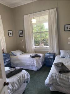 une chambre avec trois lits et une fenêtre dans l'établissement Tui Ridge Cottage, à Waiterimu