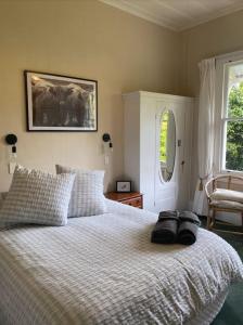 a bedroom with a bed with two black towels on it at Tui Ridge Cottage in Waiterimu