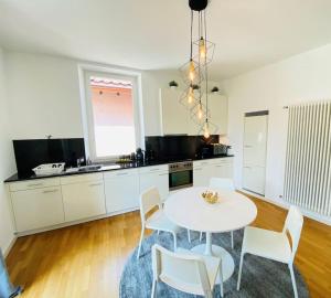 a kitchen with a white table and white chairs at GIOIA@HOME in Locarno