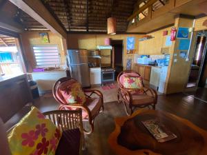 a living room with chairs and a table and a kitchen at Beach de rêve de moorea in Hauru