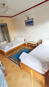 a bedroom with two beds and a rug at Hotel Mountain View - Lakeside Pokhara in Pokhara