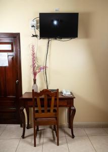 a wooden desk with a chair and a television on a wall at Hotel Internacional Palmerola in Comayagua