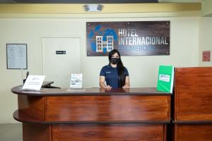 科馬亞瓜的住宿－Hotel Internacional Palmerola，戴面具的女人站在桌子后面