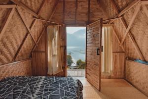 ein Schlafzimmer mit einem Bett in einem Zimmer mit einem Fenster in der Unterkunft D' Tepi Danau Glamping in Kintamani