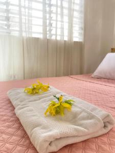 2 toallas con flores encima de una cama rosa en Balai Lawaan Cozy Homestay, en Iloilo City