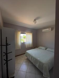 1 dormitorio con cama y ventana en Casa 3Jotas, en Garopaba