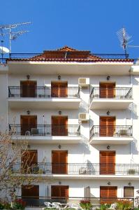 un edificio alto y blanco con balcones. en Hotel Orfeas, en Delfos