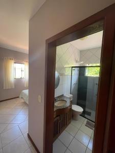 uma casa de banho com um chuveiro, um lavatório e um WC. em Casa 3Jotas em Garopaba