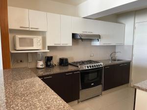 a kitchen with white cabinets and a stove and a microwave at Book in Miraflores - Lima in Lima