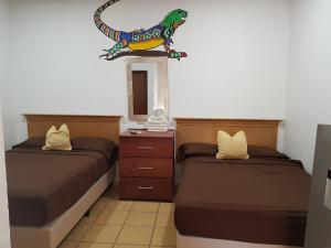 a bedroom with two beds and a dinosaur sign on the wall at Bungalows Lulu in Bucerías