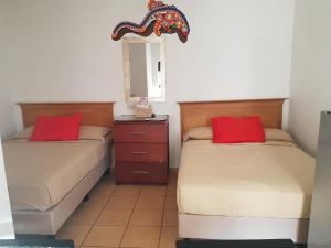 a bedroom with two beds with red pillows and a mirror at Bungalows Lulu in Bucerías