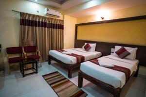 a hotel room with two beds and a chair at HOTEL PRAKAASH COMFORTS in Vānivilāsa Puram