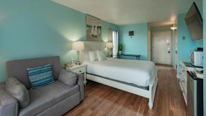 Embarcadero Resort في نيوبورت: غرفه فندقيه بسرير واريكه