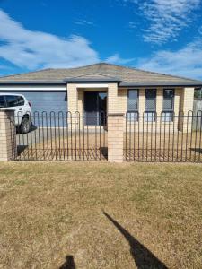 a house with a fence and a car parked in a yard at BLK Stays Guest House Deluxe Units Morayfield in Morayfield