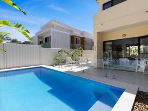 a swimming pool in front of a house at Noosa Dreaming in Noosa Heads