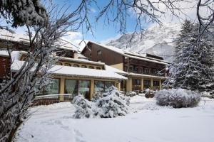 a building covered in snow with a mountain in the background at Palace Hotel Wellness & Beauty in Bormio