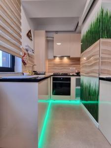 uma cozinha com luzes verdes no chão em Faleza Nord apartament de lux nou pe malul marii em Constança
