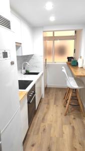 una cucina con armadietti bianchi e pavimenti in legno di Miramar Beach Apartment a El Médano