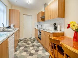 a kitchen with wooden cabinets and a checkered floor at Lime House in Gorseinon