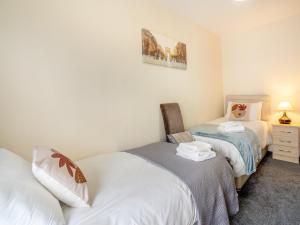 a bedroom with two beds and a desk with a lamp at Lime House in Gorseinon