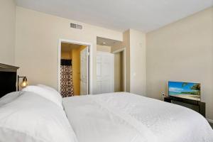 a bedroom with a white bed and a flat screen tv at Luxury 2BR/2BA!5Min to Disney! Angelstadium! HondaCenter. in Anaheim