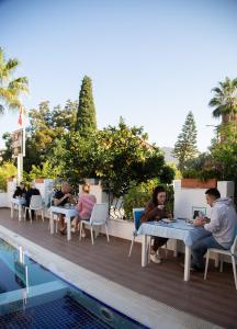 a group of people sitting at tables next to a pool at Amsterdam Otel & Suite Apart in Kemer