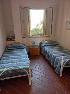 2 camas en una habitación con ventana en La casa di Giorgia a Capo Vaticano, en Capo Vaticano