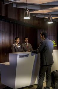 a man standing at a counter with three people at Rodas An Ecotel Hotel in Mumbai