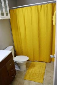 a bathroom with a yellow shower curtain and a toilet at The Little Amazon in Montgomery