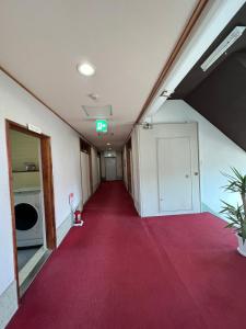 an empty hallway with a red carpet in an office building at HOSTEL OE in Yoshinogawa