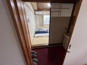 a small room with a bed and a mirror at HOSTEL OE in Yoshinogawa