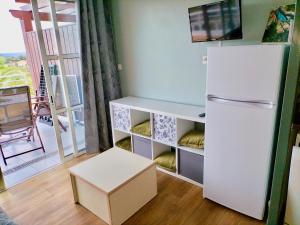 Il comprend une cuisine équipée d'un réfrigérateur blanc et d'un tabouret. dans l'établissement Superbe Appartement avec vue Mer et Piscine, à Saint-Raphaël